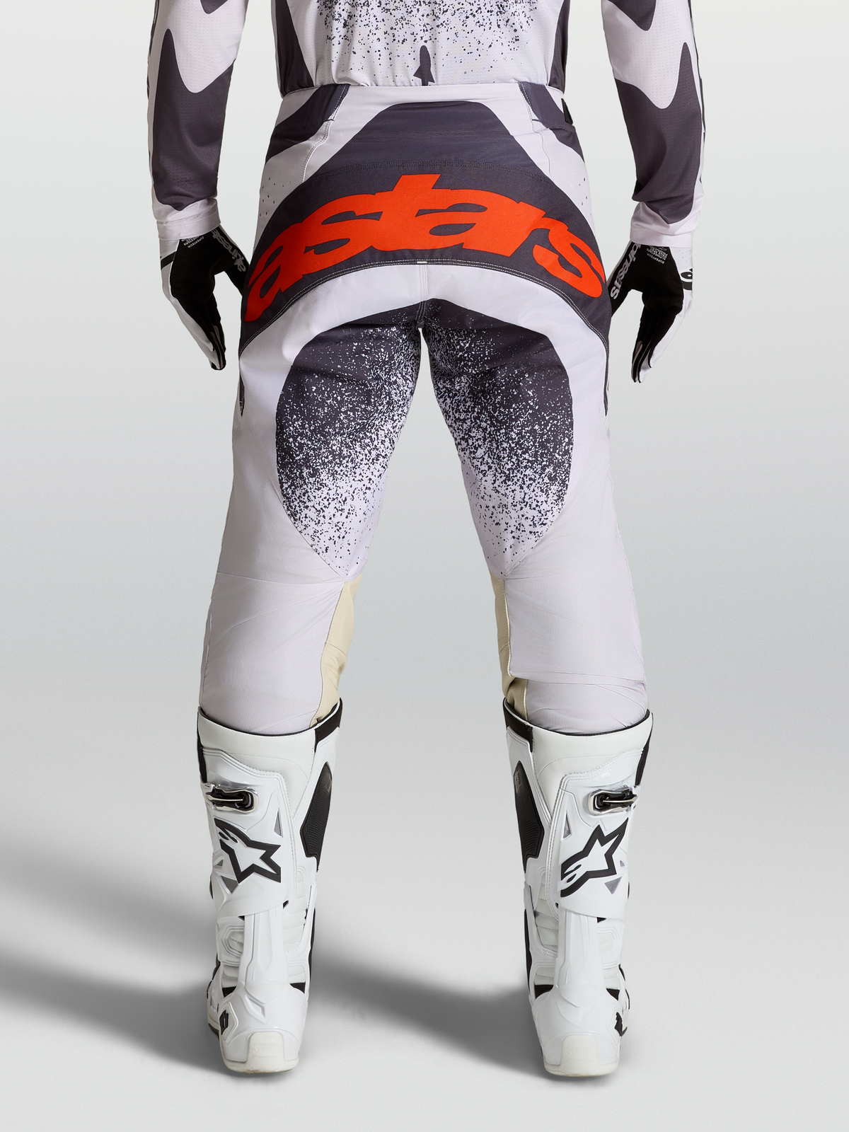Calças Techstar Swan da Alpinestars, calças de motocross para homem, lilás claro e cinzento, vista traseira com logótipo vermelho na zona do assento, design de competição off-road