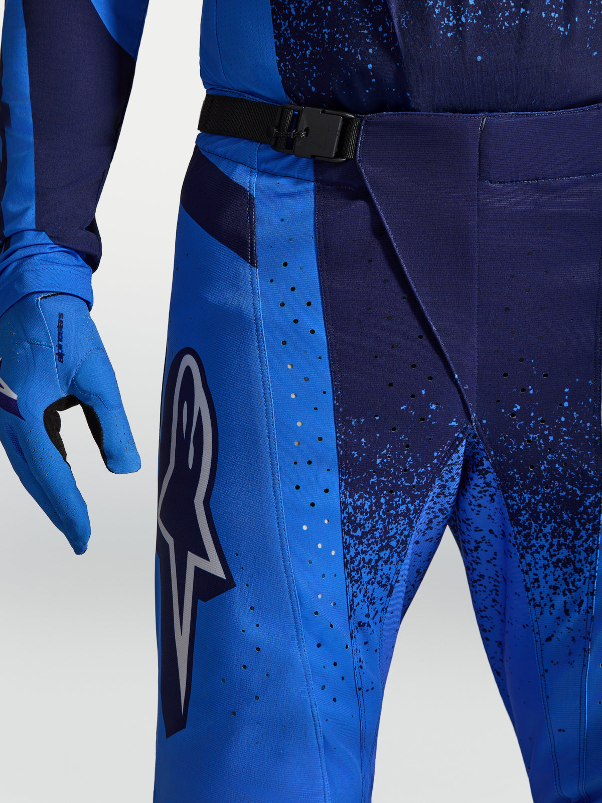 Alpinestars Techstar Swan, calças de motocross azuis com ventilação perfurada a laser e fivela magnética na cintura.
