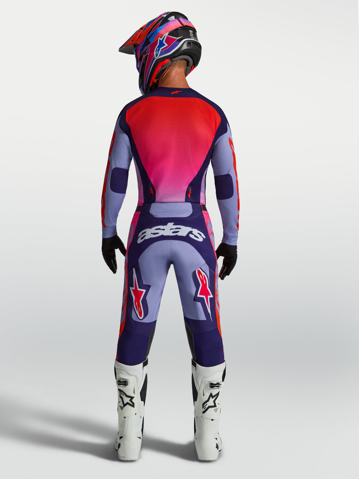 Alpinestars Calças Racer Air Hunt, calças de motocross, roxas e rosa, vista traseira no modelo, ventiladas com logótipo Astars.