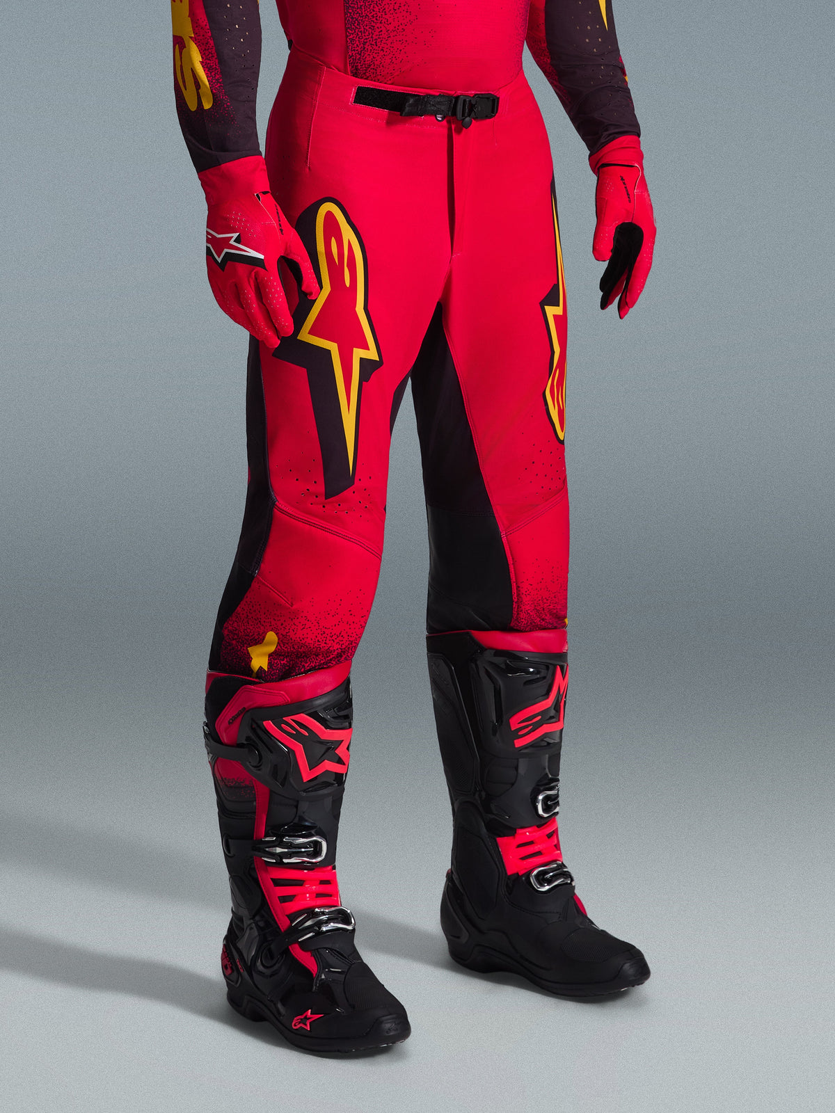 Alpinestars 2026 Supertech Scenz Pants, calças de motocross, vermelhas, pretas e amarelas, com logótipos Alpinestars amarelos e painéis pretos, usadas com camisola vermelha a condizer, luvas vermelhas e botas de motocross pretas