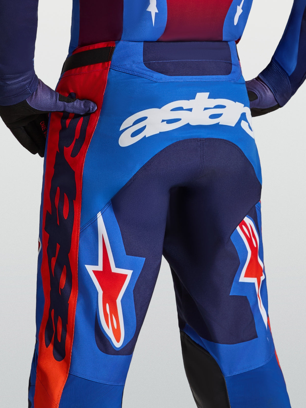 Calças Alpinestars Racer Hunt de motocross para homem, azuis e vermelhas com logótipo Astars branco e estrelas.