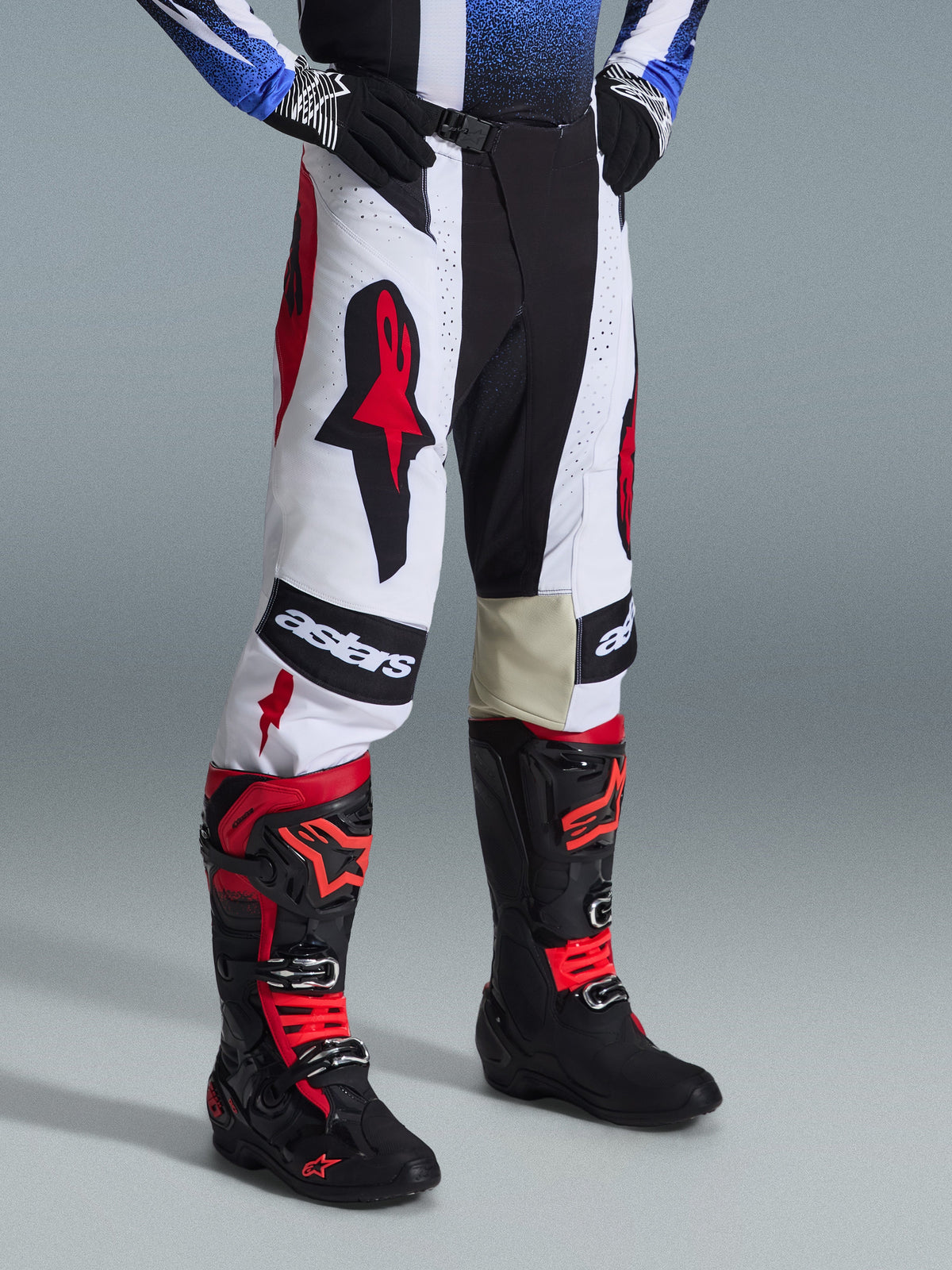 Alpinestars 2026 Techstar Knif Pants, calças de motocross, pretas, brancas e vermelhas, usadas com botas de motocross pretas e vermelhas, com logótipo Astars em destaque nas coxas, ajuste atlético de corrida e construção durável em múltiplos painéis para competição todo-o-terreno