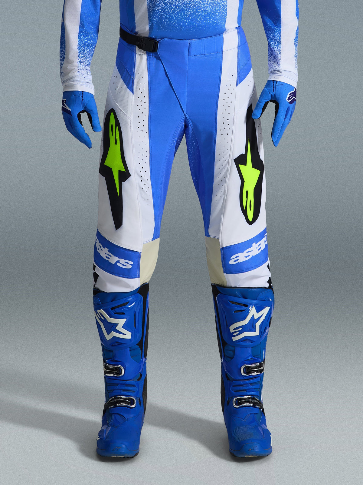 Alpinestars 2026 Techstar Knif Pants, calças de motocross, azul UCLA, preto e amarelo fluo, usadas com luvas e botas azuis a condizer, com painéis brancos e logótipos vibrantes em amarelo fluo, corte de corrida ergonómico para desempenho todo-o-terreno