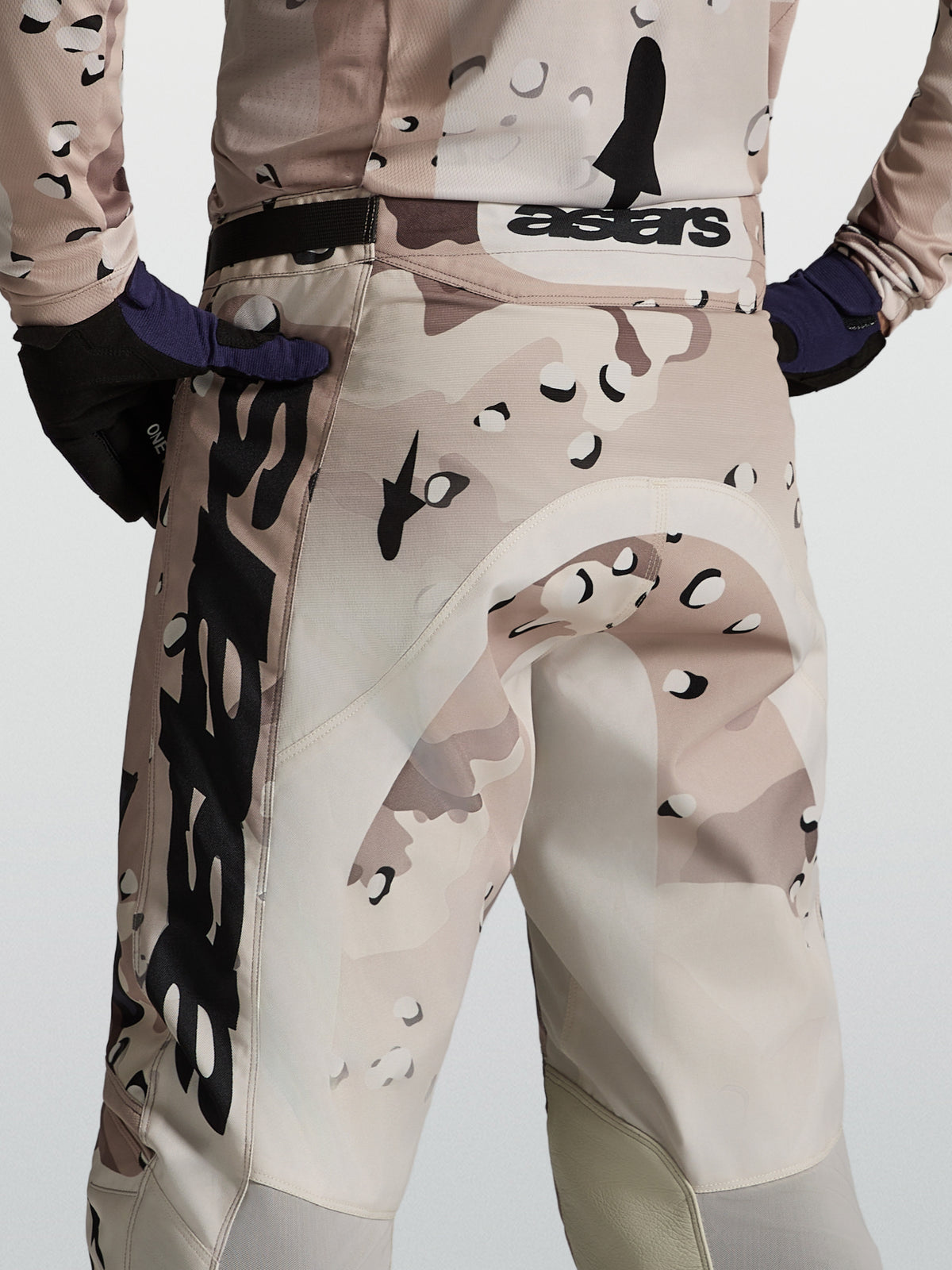 Alpinestars Calças Racer Lone, calças de motocross para homem em camuflado deserto e preto, vista traseira no modelo mostrando o ajuste de corrida e performance.