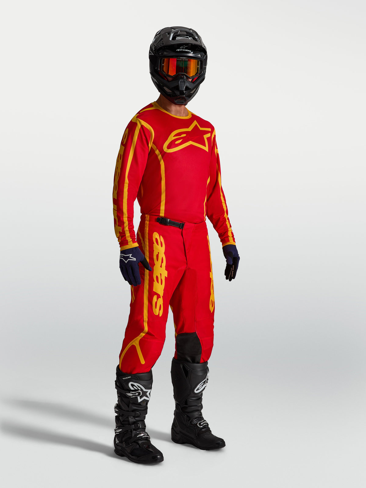 Alpinestars Calças Fluid Apex V2, calças de motocross para homem, vermelhas e douradas, modelo com camisola e botas.