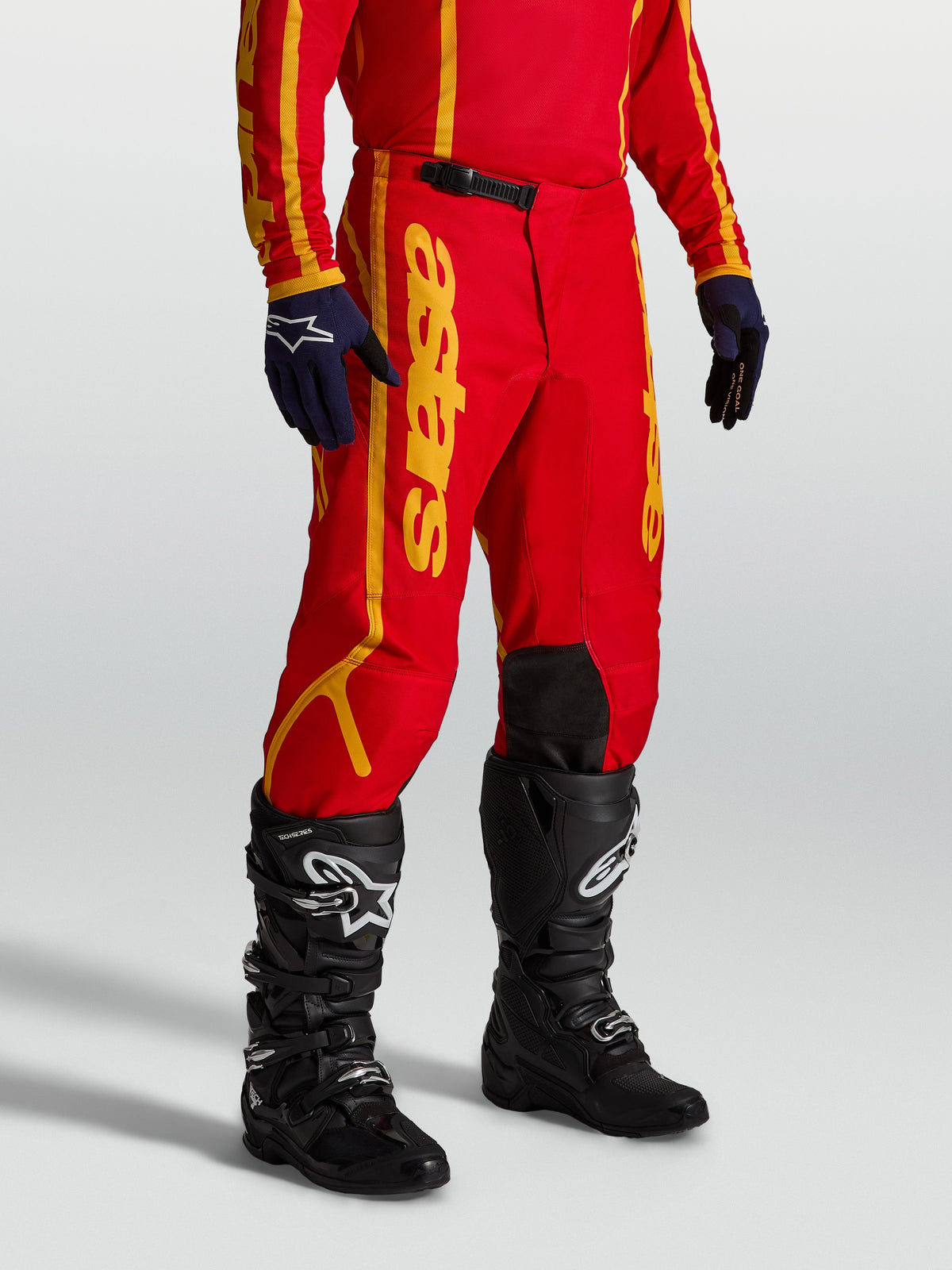 Alpinestars Fluid Apex V2, calças de motocross para homem, vermelhas e douradas, construção em polifabric 600D reforçado com fecho de catraca, modelo a usar equipamento completo