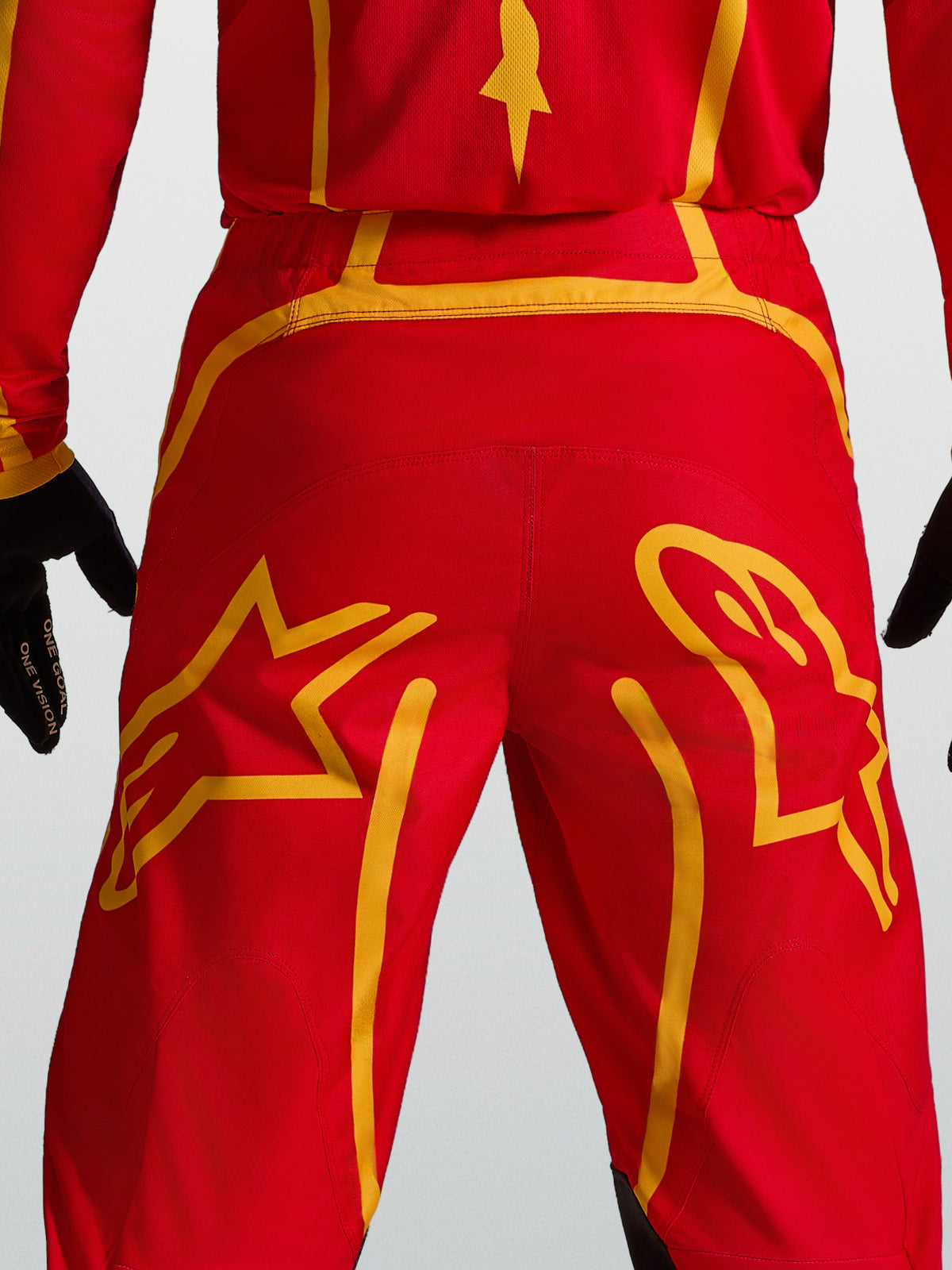 Calças Alpinestars Fluid Apex V2 para homem, de motocross, vermelhas e douradas, com gráficos de estrela na pala traseira.