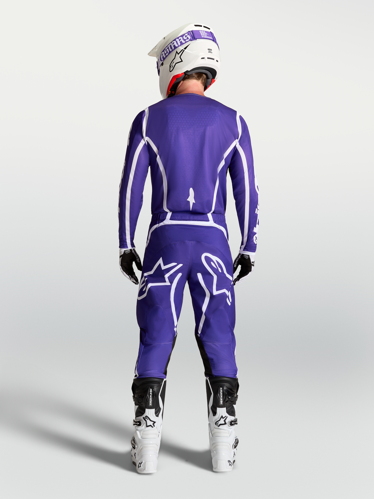 Alpinestars Fluid Apex V2, calças de motocross para homem em azul e branco, vista traseira no modelo com botas brancas.