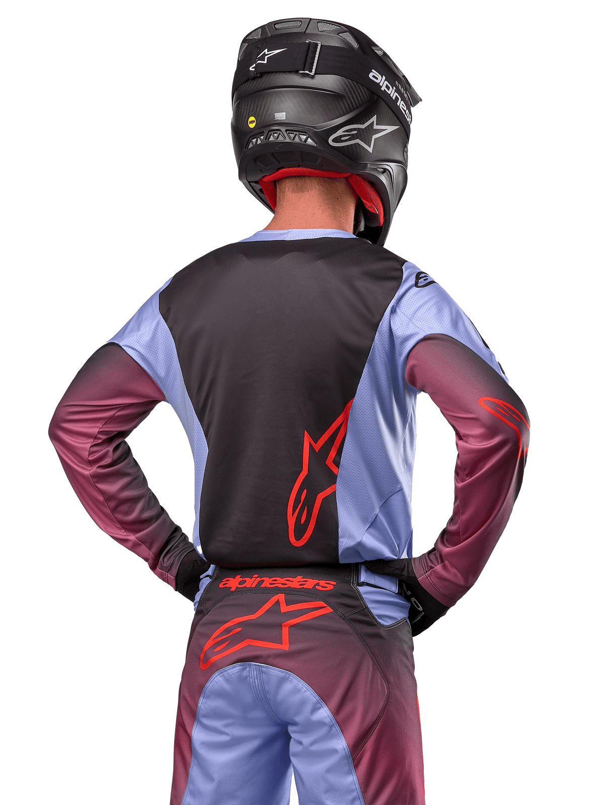 Piloto de motocross visto de costas com equipamento Alpinestars 2024 Racer Hoen, camisola roxo Lavan e preta com logótipo vermelho, calças a condizer com detalhes vermelhos, capacete preto, conjunto coordenado para competição todo-o-terreno