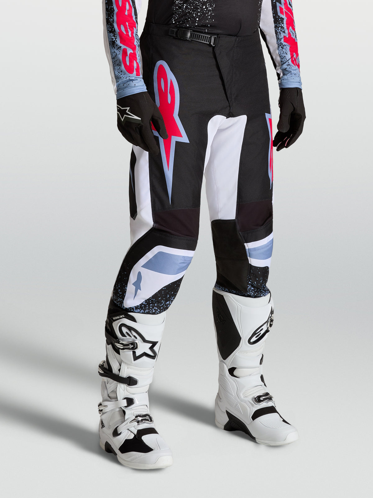 Alpinestars Calças Fluid Drag, calças de motocross para homem, pretas e brancas com pormenores em vermelho fluorescente e azul claro, construção ergonómica pré-curvada para performance todo-o-terreno.