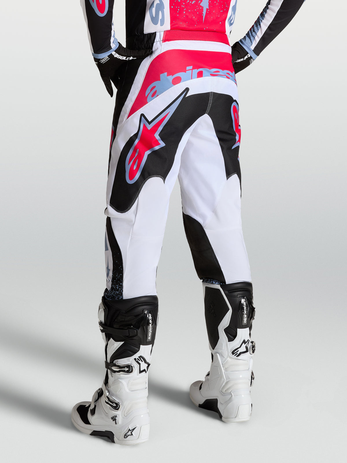 Alpinestars Calças Fluid Drag, calças de motocross para homem, brancas e pretas com detalhes em vermelho e azul claro, vista traseira no modelo
