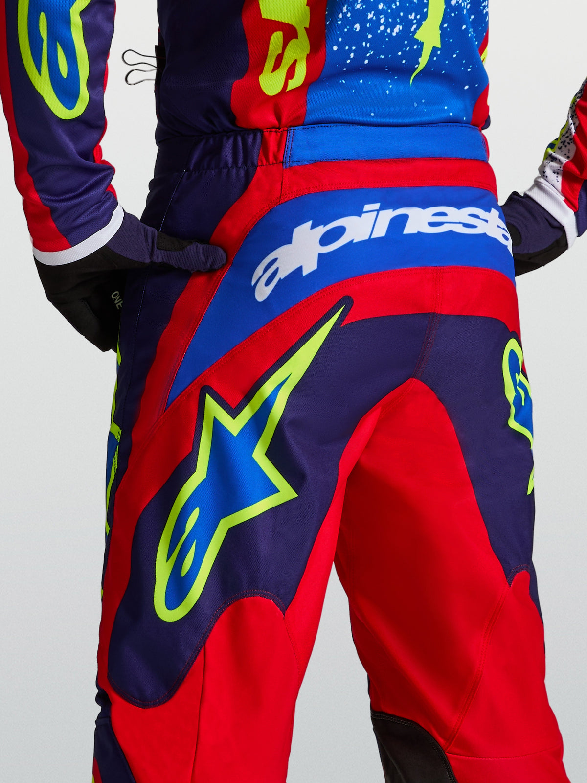 Alpinestars Calças Fluid Drag, calças de motocross para homem, azul-marinho e vermelhas, vista traseira com gráficos de estrela e ajuste desportivo.