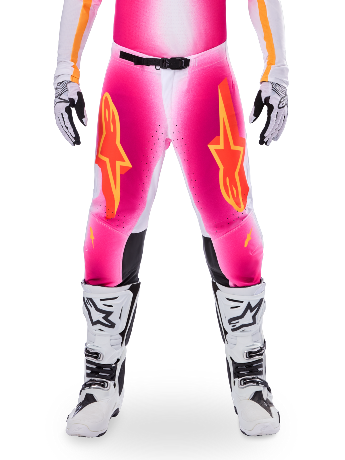 Alpinestars Limited Edition Supertech AFD MIG Pants, calças de corrida de motocross, rosa flúor e branco com detalhes laranja, logótipos de estrela grandes nas coxas, painéis perfurados e zonas de aderência pretas nos joelhos, usadas com botas de motocross brancas e pretas
