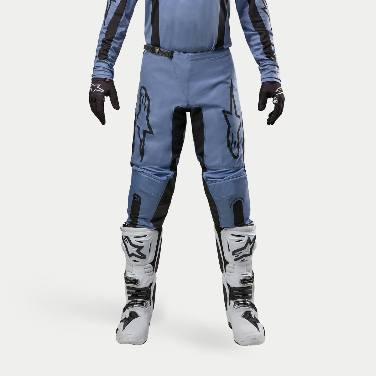 Alpinestars 2024 Fluid Lurv Pants, calças de motocross, azul claro e preto, usadas com botas de corrida brancas e pretas e luvas a condizer, com logótipos de estrela pretos destacados nas coxas, design ergonómico para performance todo-o-terreno