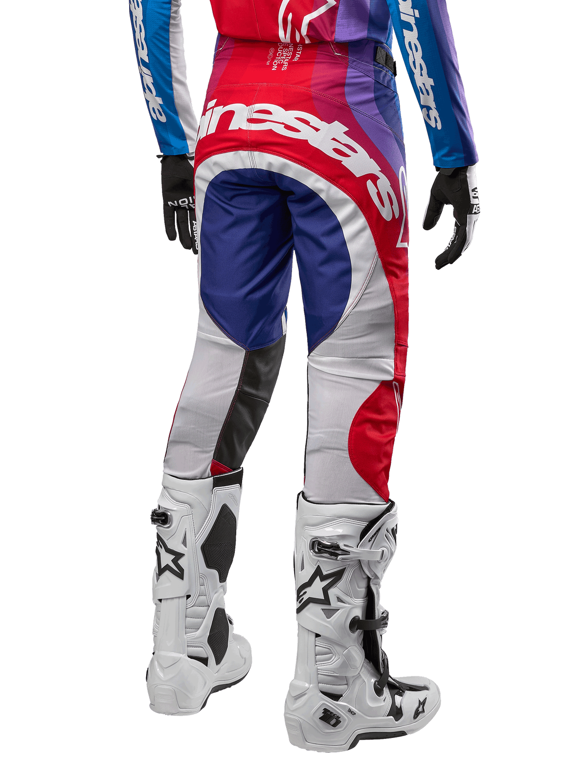 Alpinestars 2024 Techstar Pneuma Pants, calças de motocross, azul, vermelho e branco, vista traseira usadas com camisola a condizer e botas brancas, com logótipo branco em destaque no assento e painéis multicor, vestuário profissional de motocross
