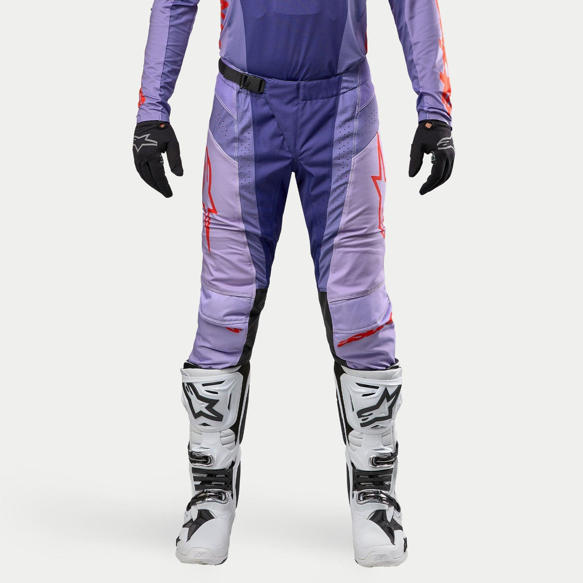 Alpinestars 2024 Techstar Ocuri Pants, calças de motocross, tons de roxo com detalhes em laranja, logótipo de estrela, zonas perfuradas para ventilação, design desportivo, acompanhadas por botas brancas.