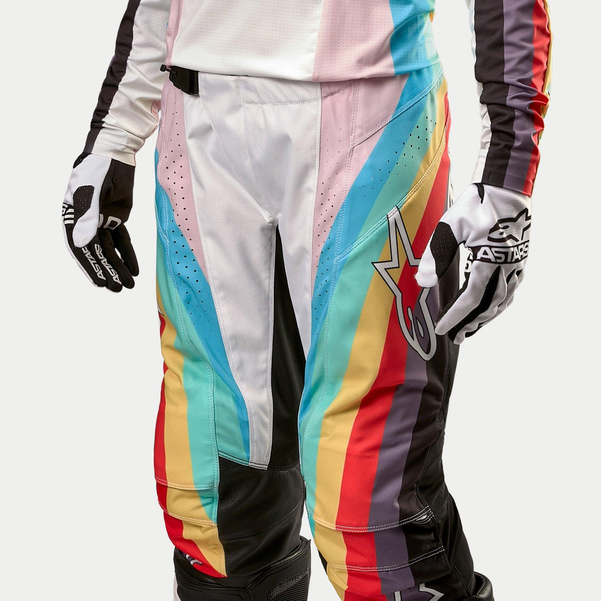 Alpinestars Women Stella 2024 Techstar Pants, Motocross Pants, Black Multicolor with vibrant diagonal stripes in blue, pink, yellow, and red, featuring a large star logo on the thigh, shown worn with matching jersey and gloves, professional off-road racing gear
