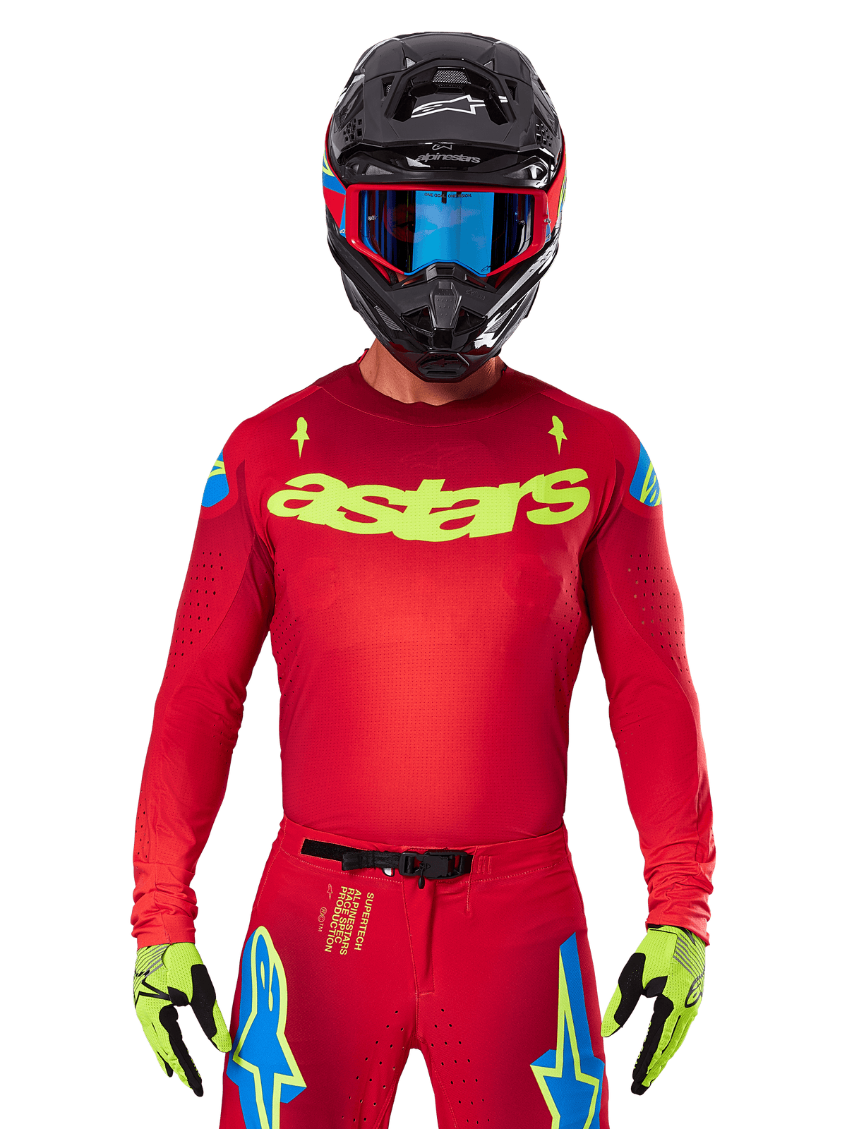 Camisola Alpinestars 2025 Supertech Maker em vermelho e amarelo fluo, com a marca "astars" amarela no peito e estrelas azuis nos ombros, usada com calças a condizer, capacete preto, óculos azuis e luvas amarelas, vestuário profissional de motocross