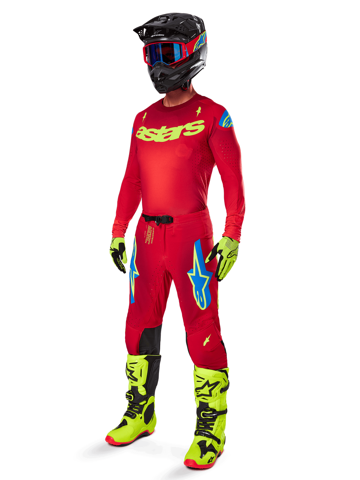 Piloto de motocross a usar a camisola 2025 Supertech Maker, em vermelho vivo com logótipos amarelo néon, calças vermelhas a condizer com detalhes azuis e amarelos, capacete preto com pormenores em azul e vermelho, botas amarelo néon e pretas, equipamento de corrida profissional coordenado para performance em todo-o-terreno