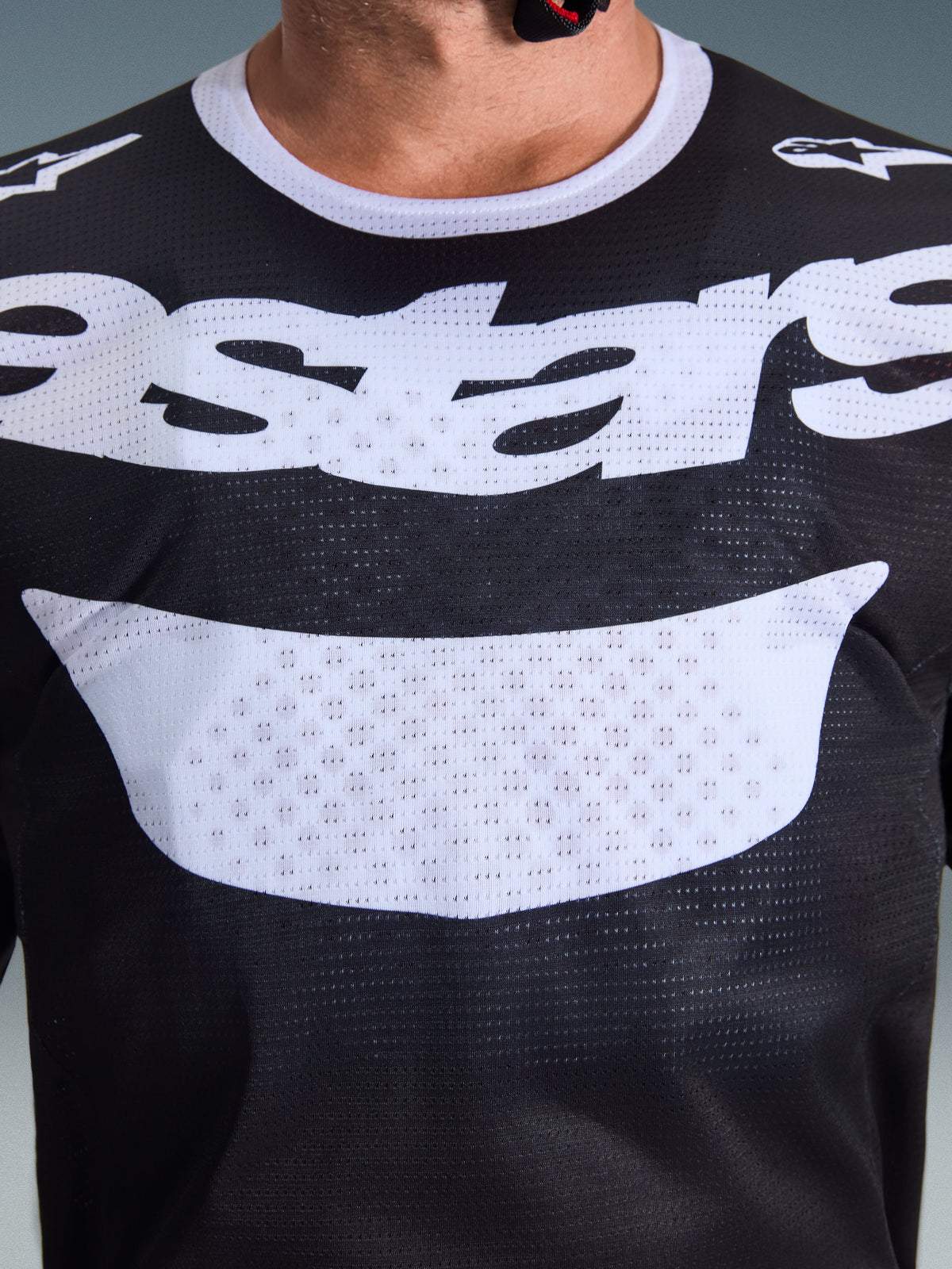 Camisola Alpinestars 2026 Racer Air Riway, camisola de motocross, preta e branca, vista em grande plano do peito com logótipo branco grande, textura detalhada do tecido de malha respirável, equipamento técnico para condução off-road