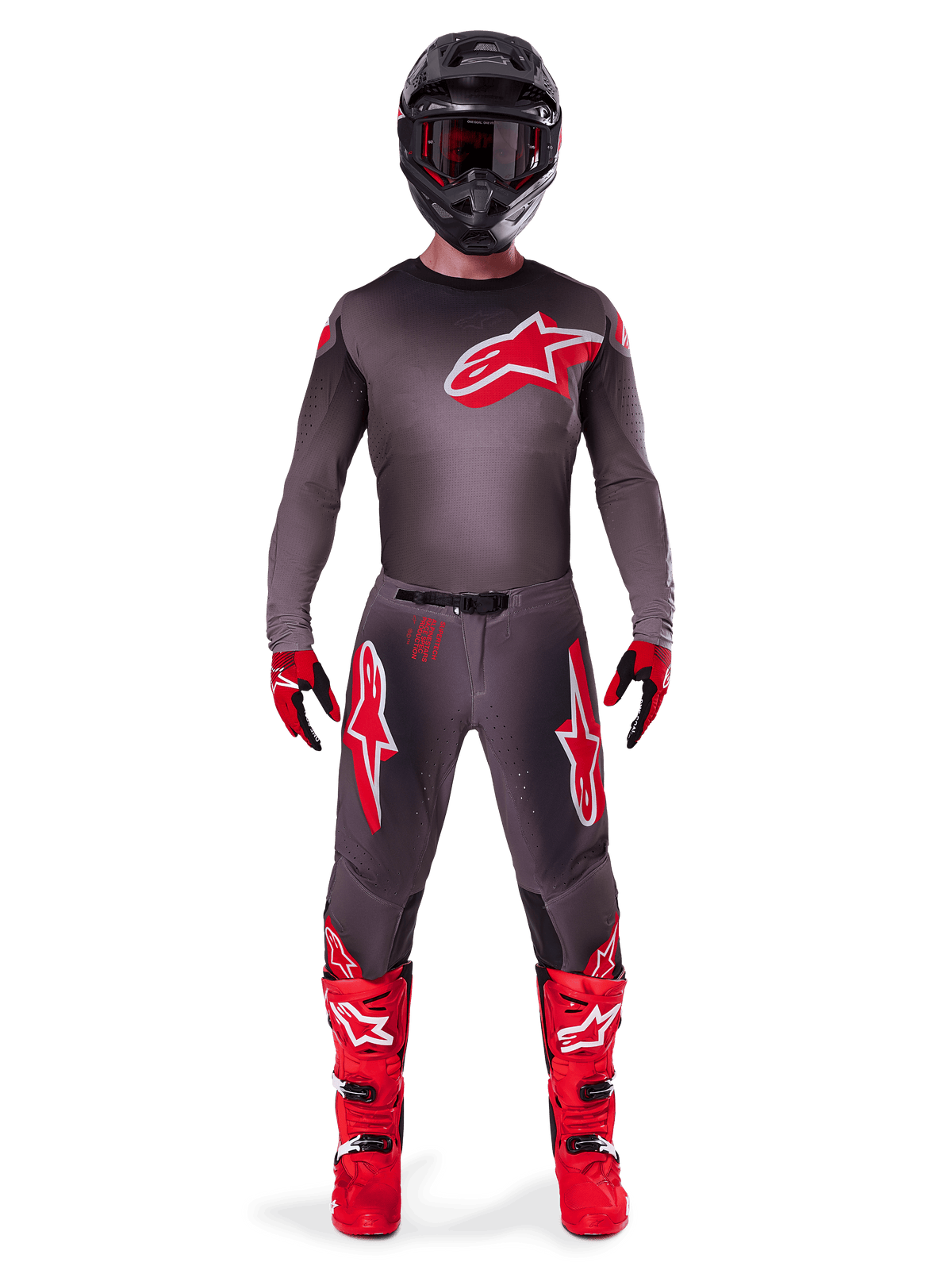 Piloto de motocross com equipamento de competição completo, camisola Supertech Lipan 2025 em Smoke Bright Red, calças cinzentas a condizer com logótipos vermelhos, botas vermelho vivo, capacete preto com óculos e luvas vermelhas e pretas, conjunto profissional de motocross.