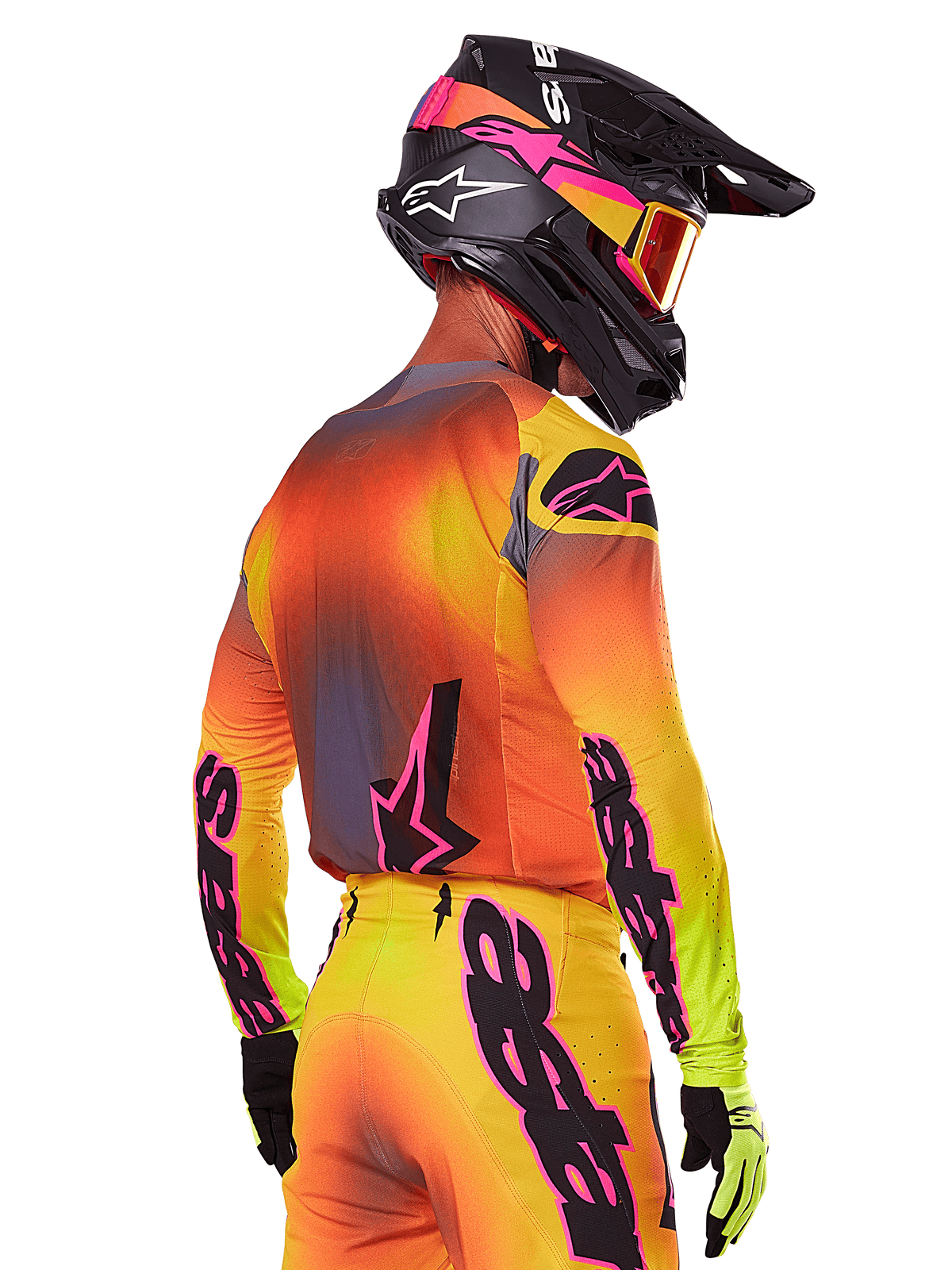 Motocross rider seen from a rear-side view wearing the Alpinestars 2025 Supertech Lipan Gear Set, featuring a yellow, orange, and red gradient with black and pink branding, black helmet with pink accents and orange goggles, professional off-road racing attire.