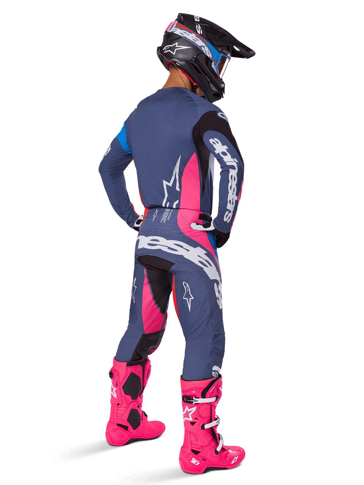 Piloto de motocross visto de costas, a usar o conjunto de equipamento Alpinestars Techstar Dreem 2025, cinzento com detalhes vibrantes em cor-de-rosa e branco, capacete preto e branco e botas cor-de-rosa brilhante, equipamento de corrida completo para performance em motocross.