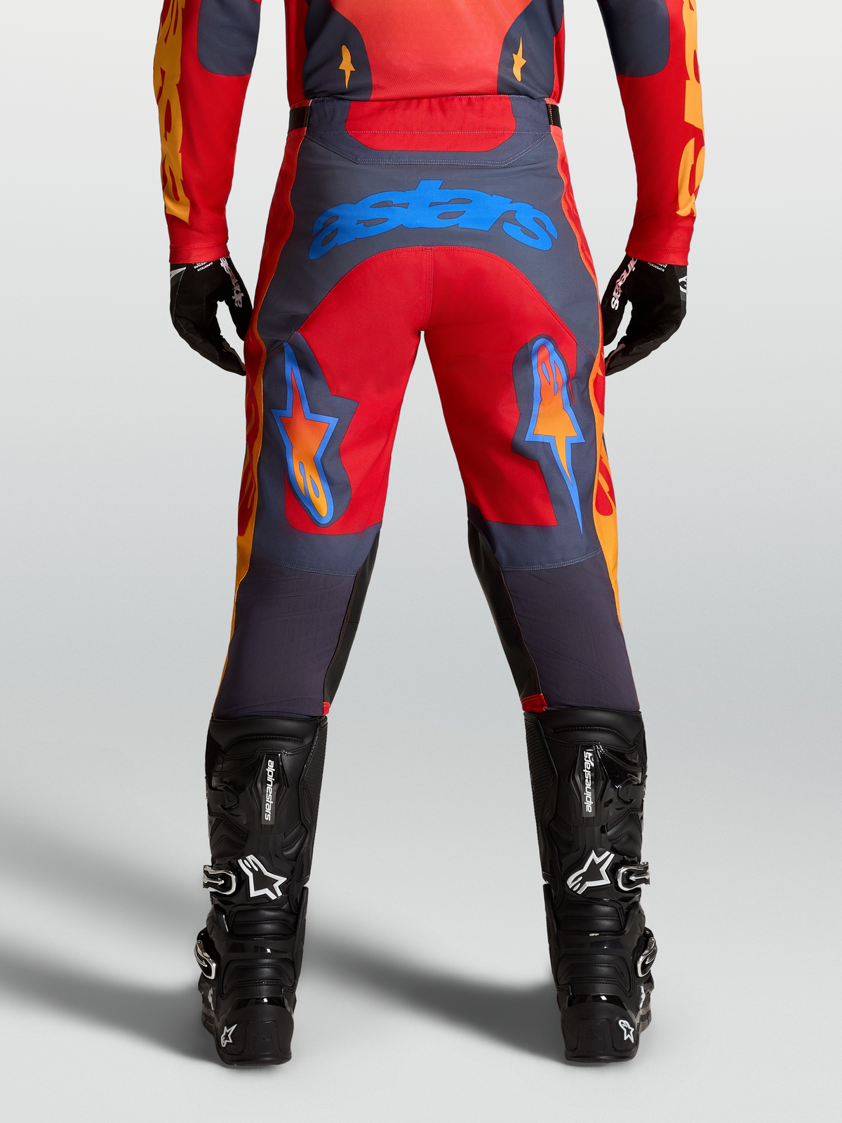 Alpinestars Calças Racer Hunt, calças de motocross para homem, vermelho e cinzento, vista traseira com logótipo azul no assento e pernas pré-curvadas