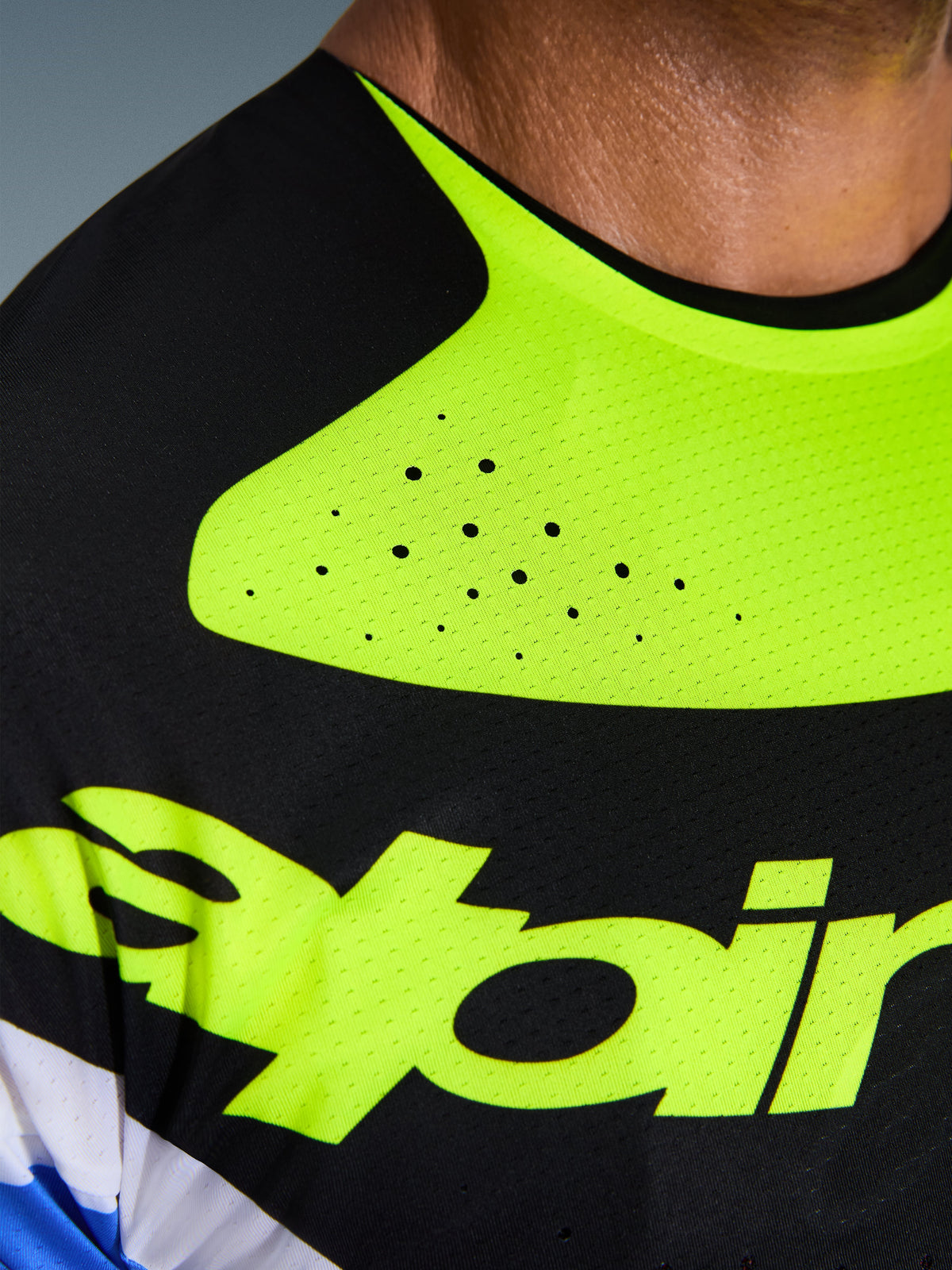 Close-up da camisola Alpinestars 2026 Techstar Knif, em preto e amarelo fluorescente, destacando as perfurações cortadas a laser para ventilação, a gola colada sem costuras e o tecido técnico de absorção de humidade com marca em amarelo.