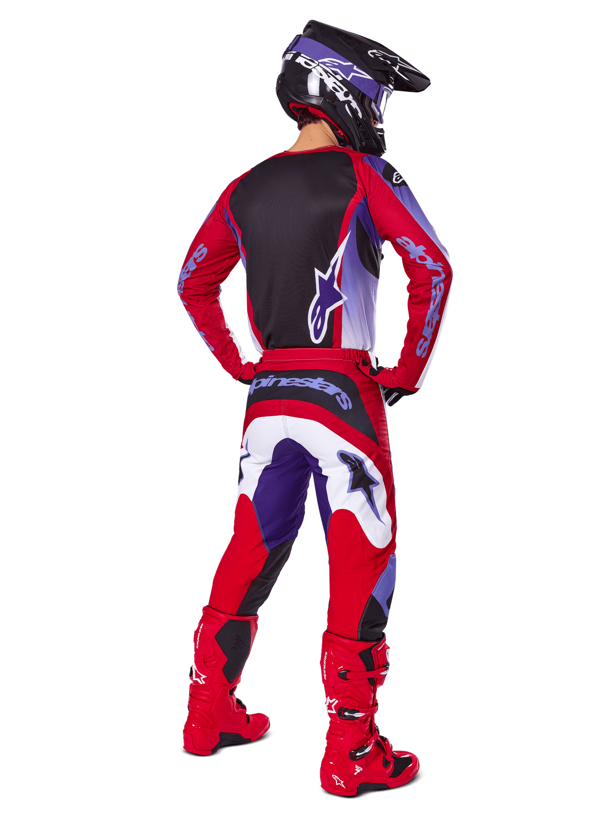 Piloto de motocross visto de costas equipado com o conjunto de equipamento Alpinestars 2025 Fluid Wurx, camisola roxa e vermelho brilhante com painel traseiro preto, calças de motocross a condizer com detalhes em branco e roxo, botas em vermelho brilhante e capacete preto, equipamento de corrida profissional de todo-o-terreno