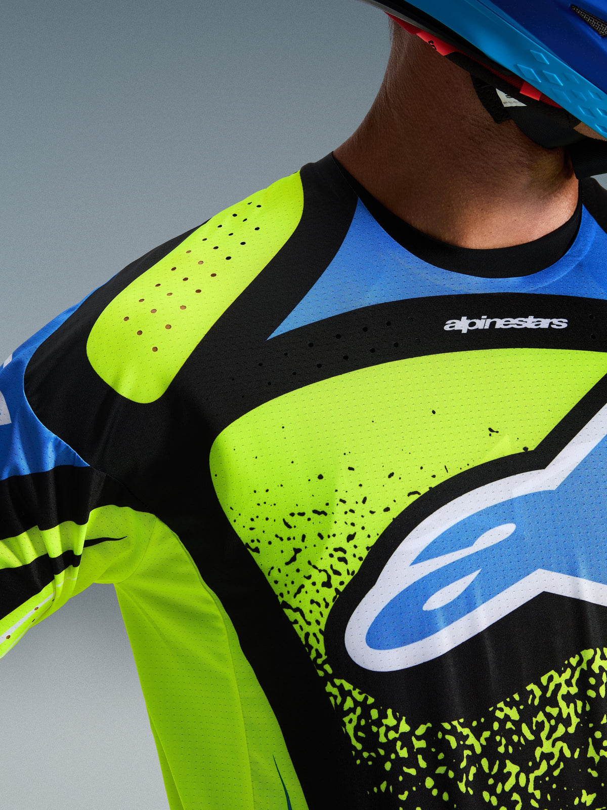 Camisola Alpinestars Techstar Nomur 2026, camisola de motocross, amarelo fluorescente, azul marinho e azul UCLA, vista detalhada do peito e do ombro com perfurações a laser para ventilação e o logótipo Alpinestars, equipamento de alta performance para todo-o-terreno