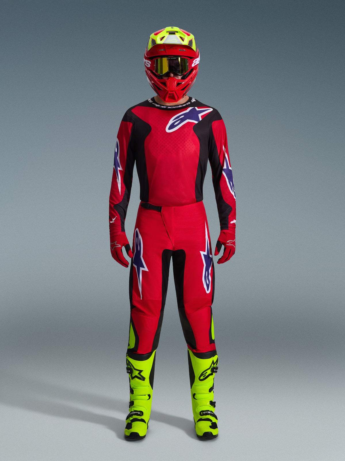 Motocross rider wearing the 2026 Fluid Grid Jersey in Red Black Purple, matching red pants with purple logos, red helmet with neon yellow accents, neon yellow boots, full coordinated racing kit for off-road motocross
