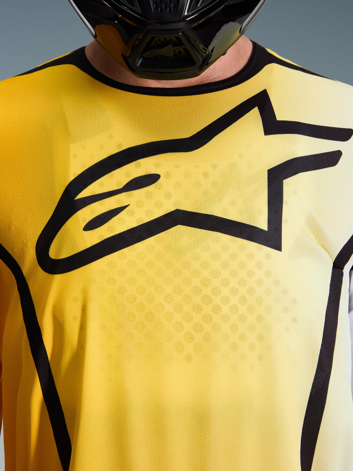 Alpinestars 2026 Fluid Apex Jersey, camisola de motocross, amarelo brilhante e preto, vista de perto com um grande logótipo Astar preto no peito, tecido de poliéster respirável que afasta a humidade e gola desportiva