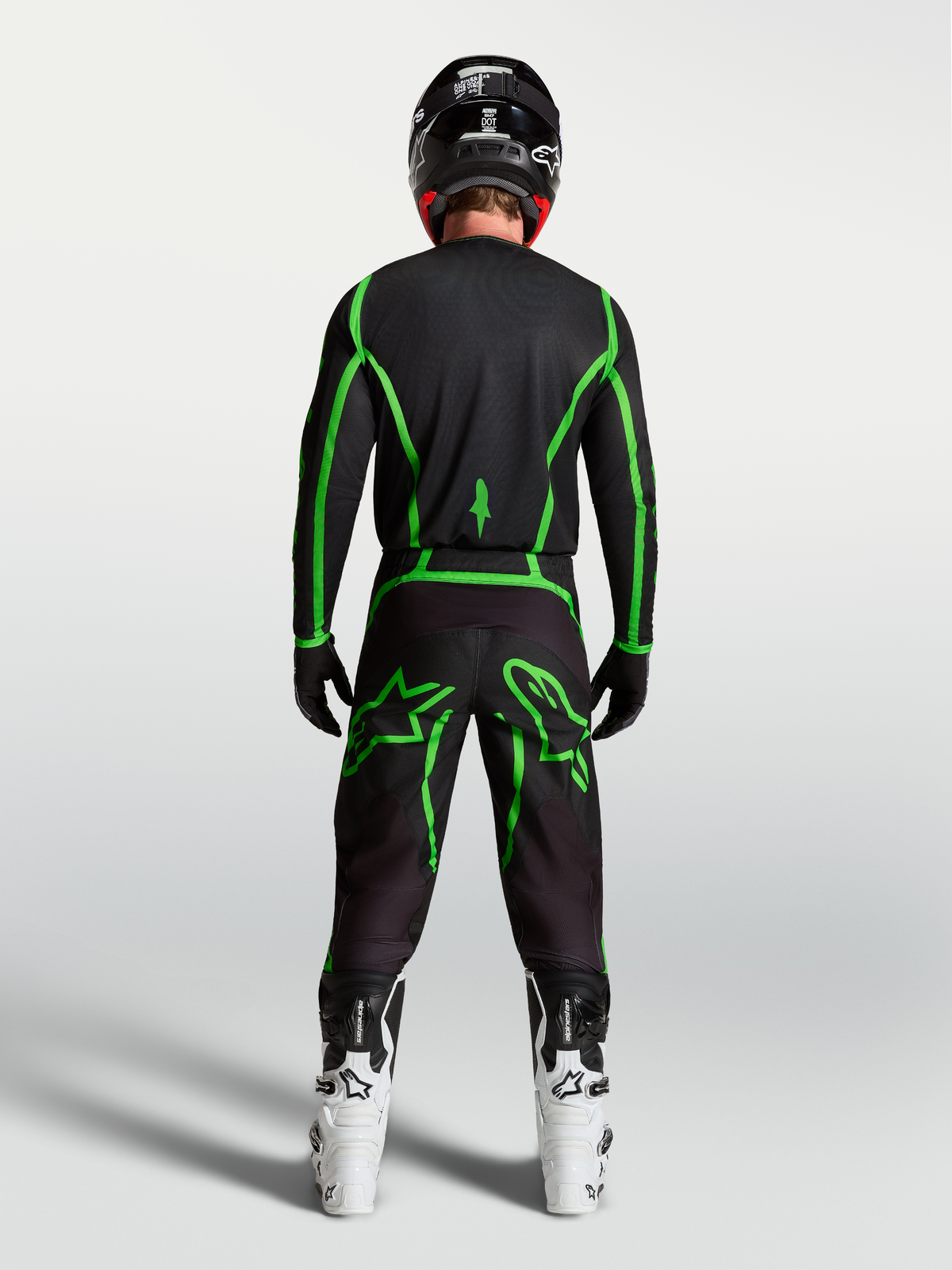 Alpinestars Fluid Apex V2, calças de motocross pretas e verdes fluorescentes, vista traseira com botas brancas.