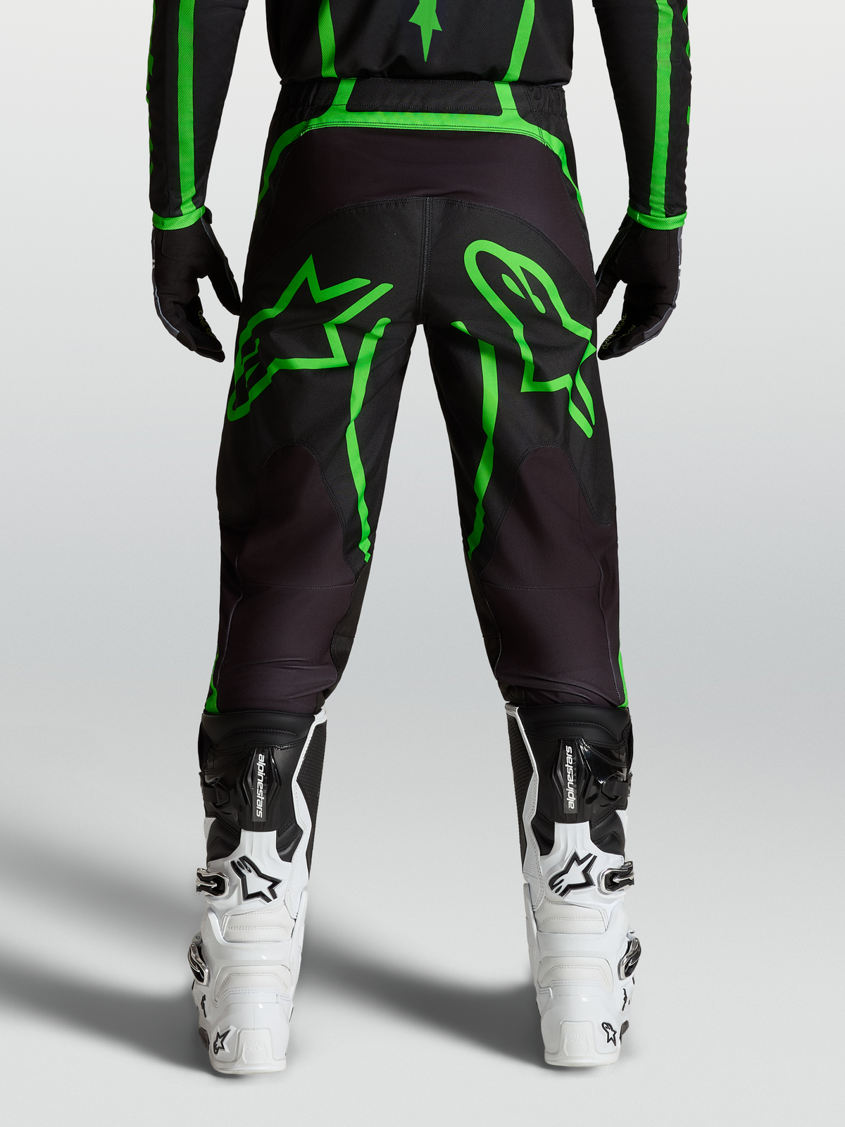Alpinestars Calças Fluid Apex V2, calças de motocross para homem, pretas e verdes florescentes, com gráficos de estrelas, vista traseira no modelo