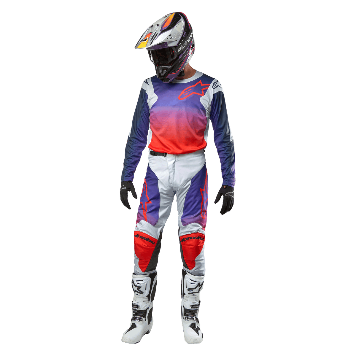 Piloto de motocross com equipamento de corrida completo, camisola Alpinestars 2024 Racer Hoen com gradiente de roxo a laranja vibrante e ombros em cinzento claro, calças em cinzento claro a condizer com detalhes em vermelho e roxo, capacete coordenado e botas brancas, conjunto de competição todo-o-terreno