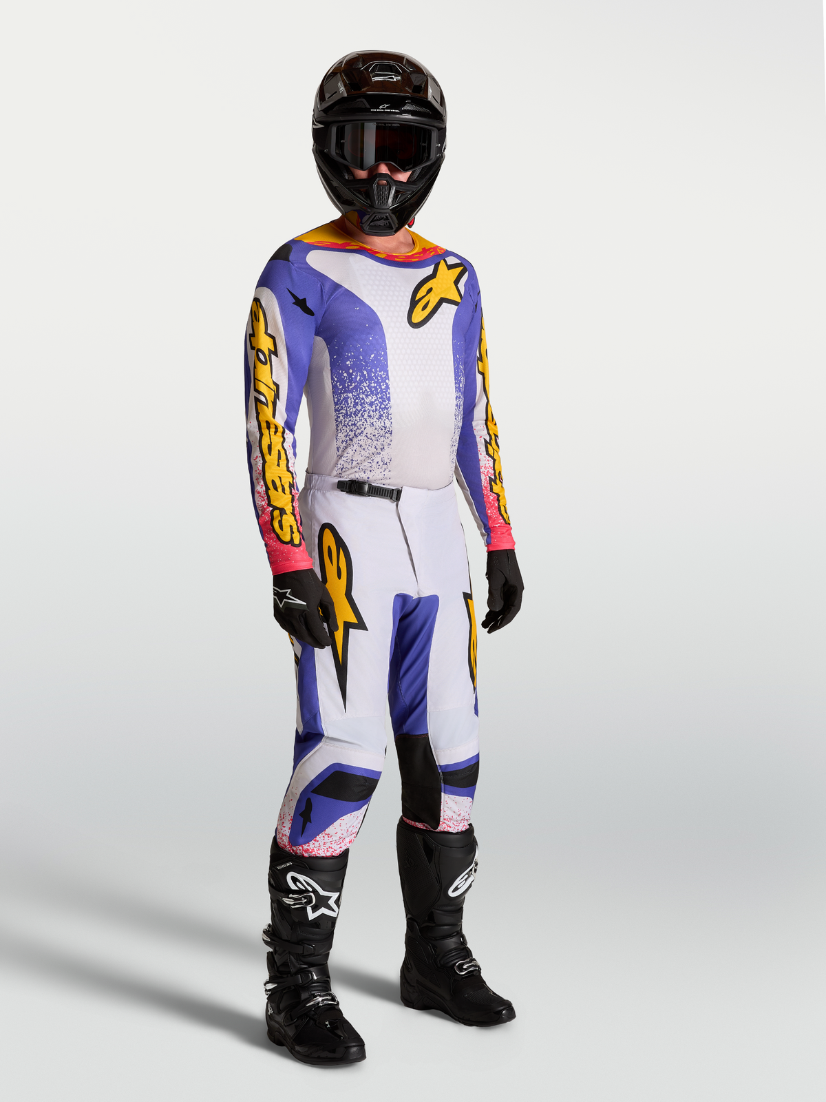 Alpinestars Fluid Drag Jersey and pants, men's motocross gear set in light lilac, blue iris, and white with black boots.