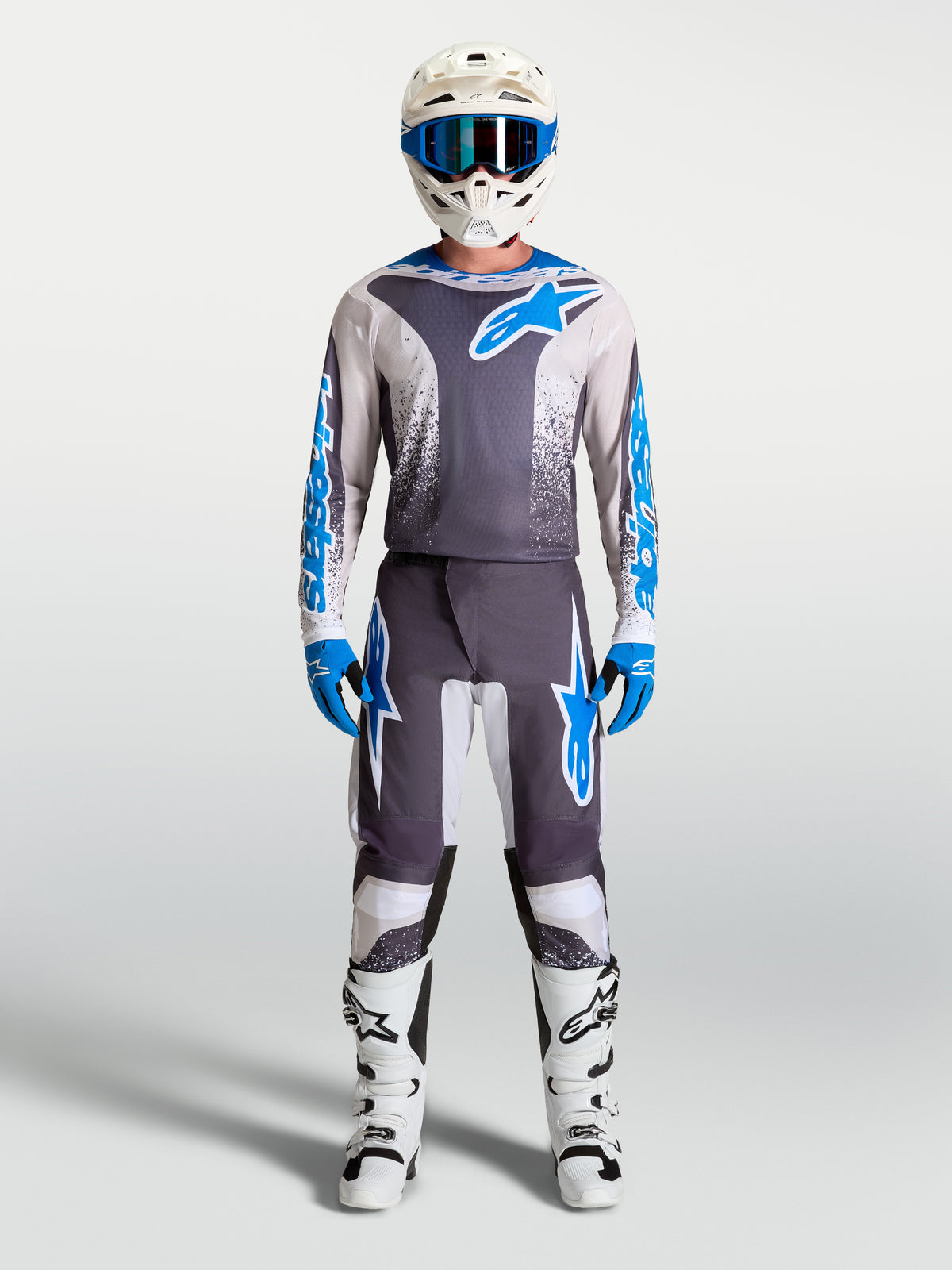 Alpinestars Fluid Drag Jersey in Graystone and Blue, worn as a motocross kit with a matching white helmet and racing boots.