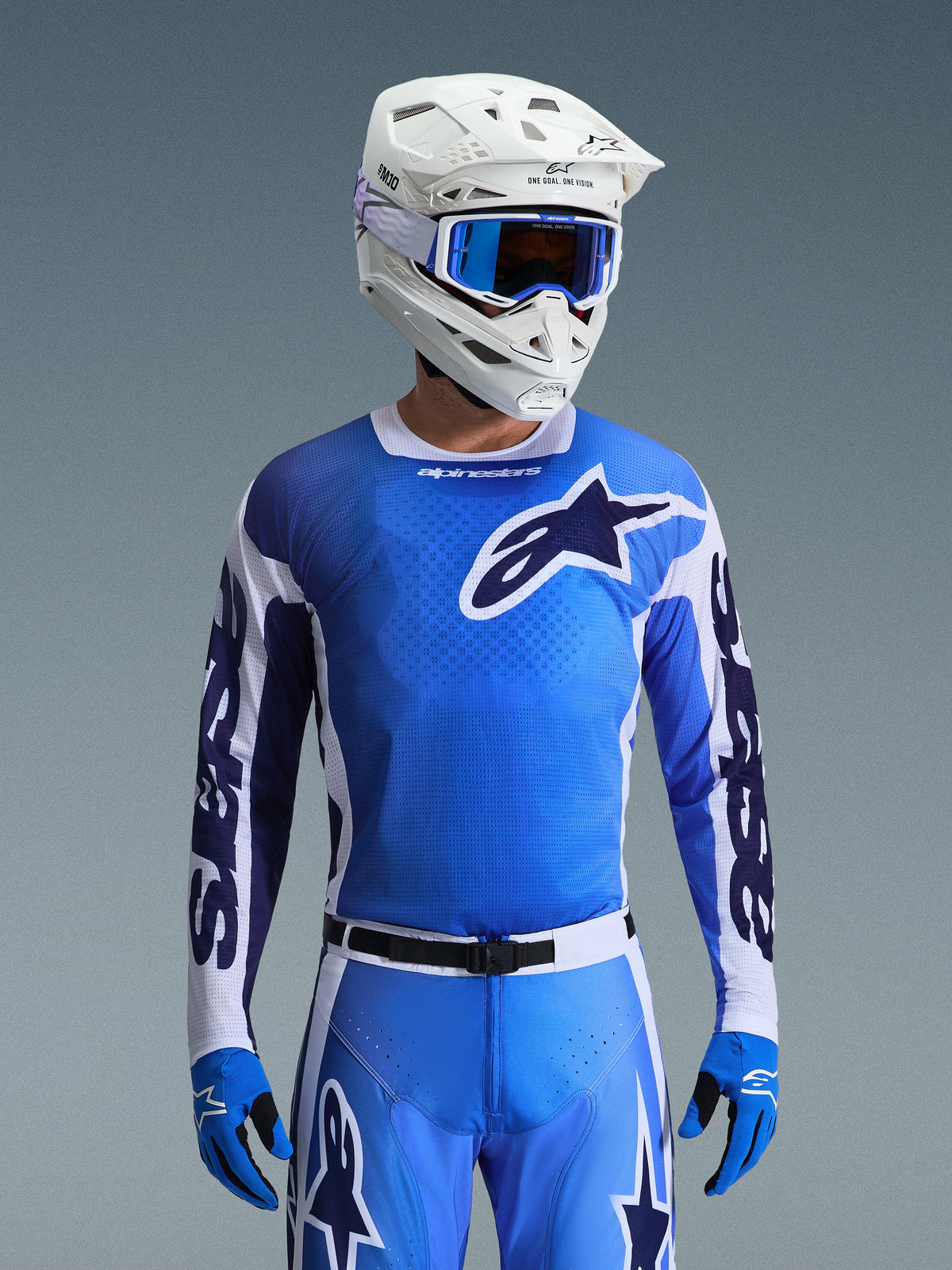 Camisola Alpinestars 2026 Racer Air Portl em Azul Ucla e Branco, camisola de motocross com construção em malha respirável e logótipo de estrela arrojado, usada por um piloto com calças a condizer, capacete branco e óculos azuis para um conjunto de equipamento de corrida off-road coordenado