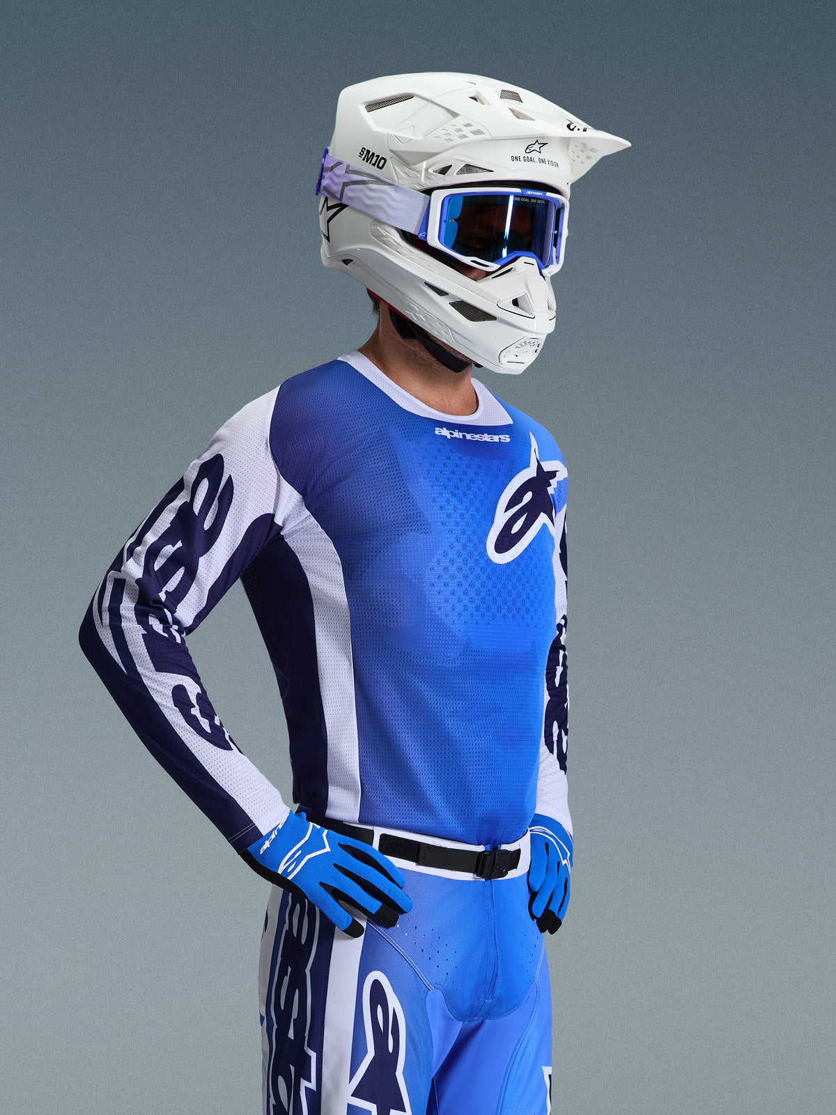 Alpinestars 2026 Racer Air Portl Jersey, camisola de motocross, azul Ucla e branco, usada com capacete branco, óculos azuis e luvas a condizer, com um design de malha respirável para corridas de motocross a altas temperaturas