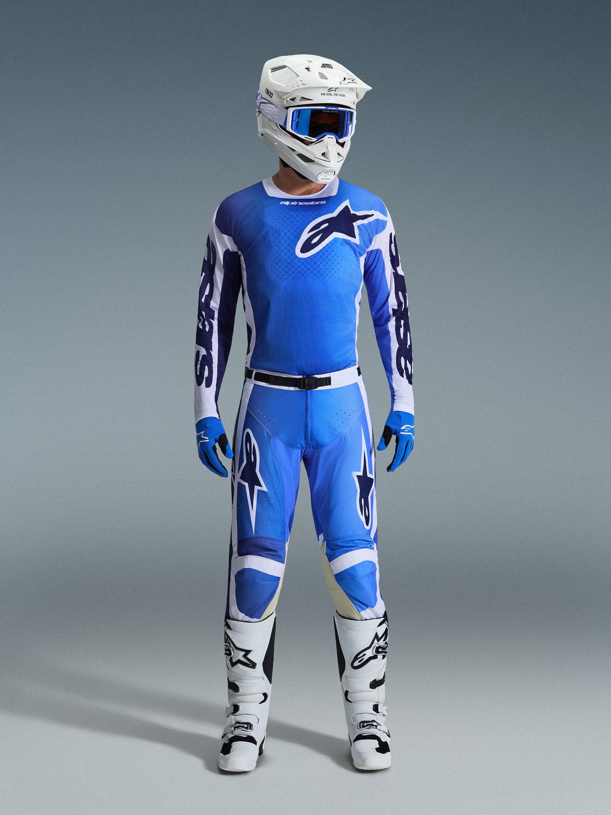 Piloto de motocross a usar a camisola Alpinestars Racer Air Portl 2026 em Ucla Blue White, combinada com calças de motocross azuis a condizer, capacete branco com óculos azuis, luvas azuis e botas brancas, conjunto de equipamento profissional completo para corridas off-road