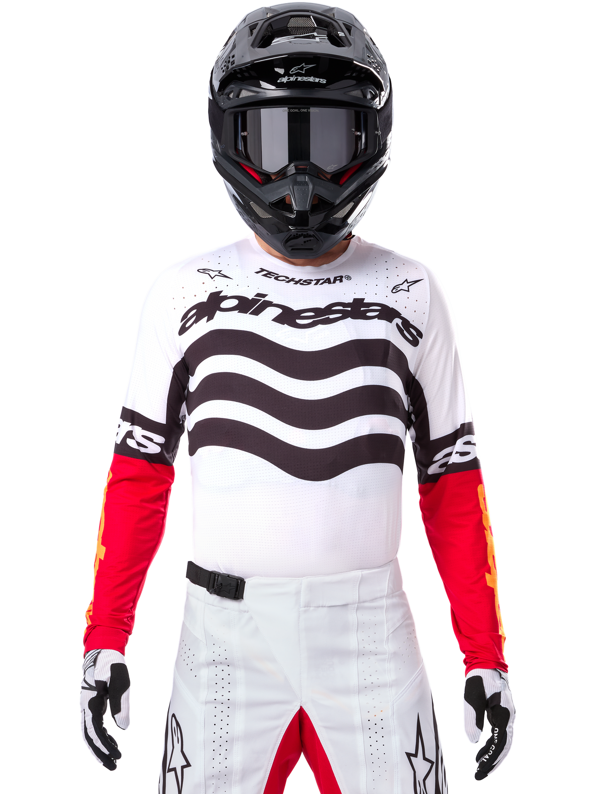 Piloto de motocross com equipamento completo, camisola Techstar Deep Edição Limitada em branco e preto com mangas vermelhas, grafismos ondulados e branding Alpinestars em destaque, calças de motocross brancas, capacete e óculos pretos, conjunto coordenado para todo-o-terreno