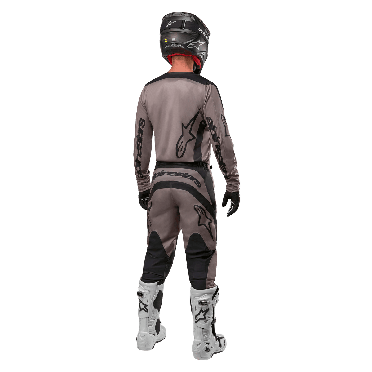 Alpinestars 2024 Fluid Lurv Jersey, camisola de motocross, Mud Black, vista traseira de piloto de motocross com equipamento de corrida a condizer, capacete preto e botas brancas, com logótipos Alpinestars em destaque e corte atlético para desempenho em todo-o-terreno