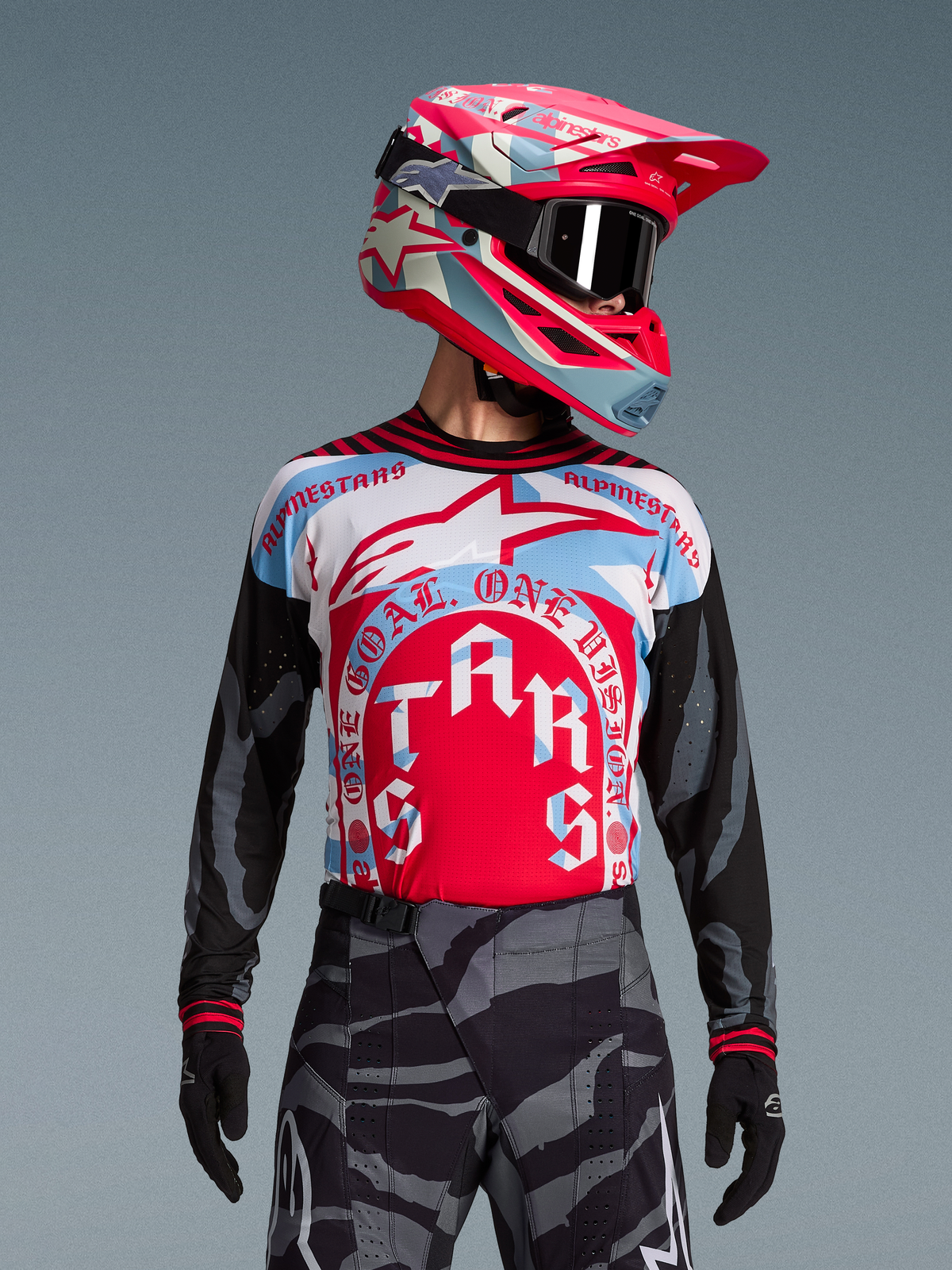 Camisola Techstar Beast Coast Alpinestars, gráfico vermelho e azul, mangas camufladas pretas e capacete de motocross a condizer.