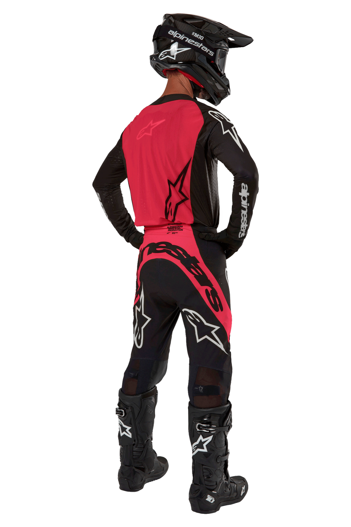 Piloto de motocross visto de costas a usar a camisola 2024 Supertech Ward em Black Red Berry, com um painel traseiro vermelho vibrante e mangas pretas com a marca Alpinestars a branco. Combinado com calças de motocross a condizer, botas Tech 10 pretas e um capacete de fibra de carbono preto para um conjunto de equipamento de corrida profissional coordenado.