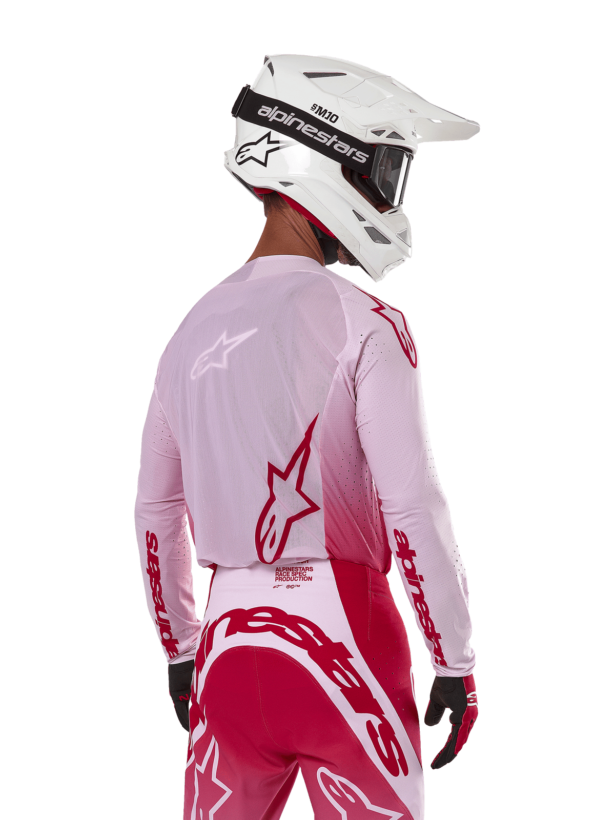 Piloto de motocross visto de costas a usar a camisola Alpinestars 2024 Supertech Dade em Red Berry Lilac, com painéis em malha respirável e logótipos Alpinestars vermelhos, combinada com calças em vermelho e lilás a condizer e um capacete Alpinestars branco com óculos, equipamento profissional de corrida todo-o-terreno