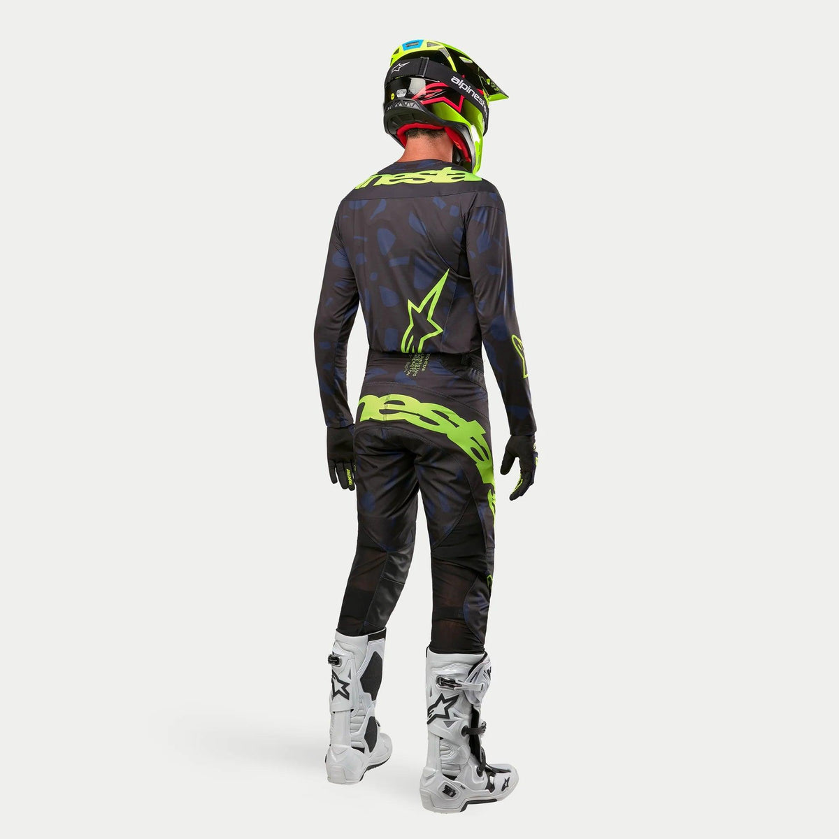Camisola Alpinestars 2024 Techstar Rantera, camisola de motocross, em preto, azul-marinho e amarelo néon, usada com calças a condizer, botas brancas e pretas e capacete amarelo néon, vista de costas com o equipamento completo de motocross
