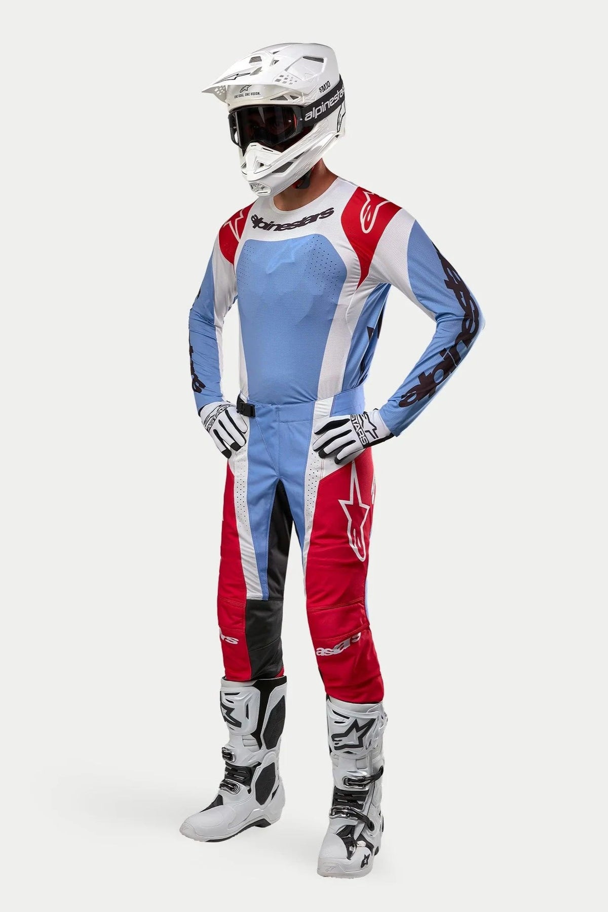 Motocross rider wearing Alpinestars 2024 Techstar Ocuri gear, Light Blue Mars Red and White jersey and pants, white helmet with goggles, white and black gloves and boots, professional racing outfit for off-road performance