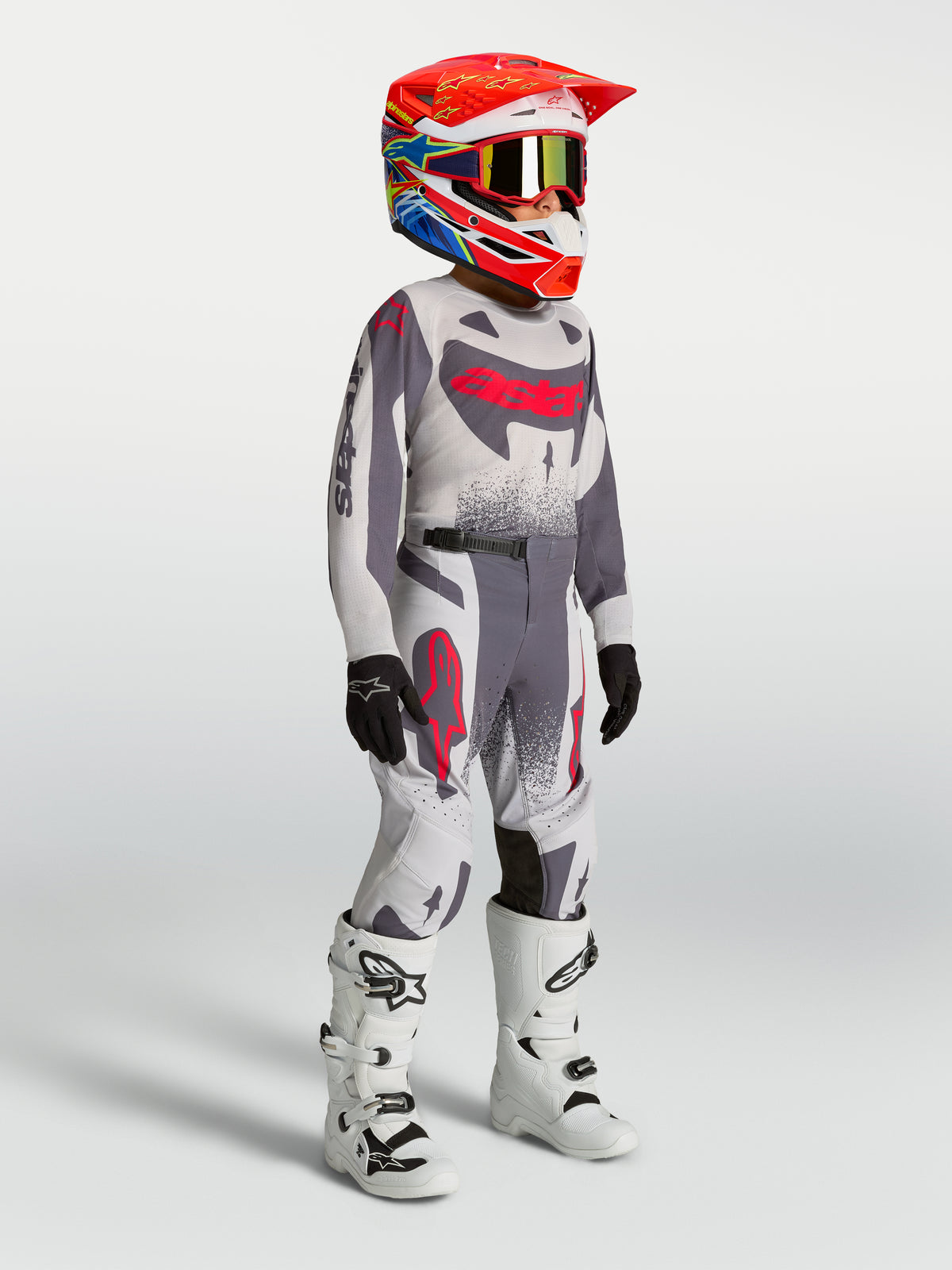 Alpinestars camisola e conjunto Supertech Swan Jovem, motocross, cinzento e vermelho fluo, com botas brancas.