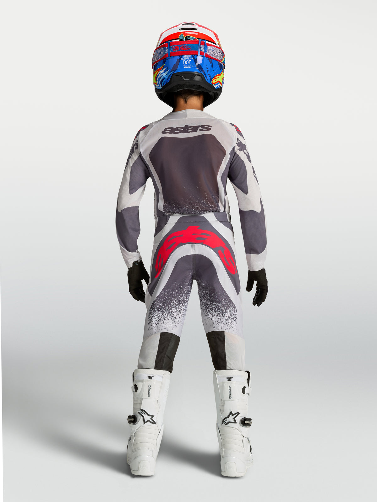 Alpinestars Juventude Supertech Swan 2027, camisola e conjunto de motocross cinzento, branco e vermelho, vista traseira.
